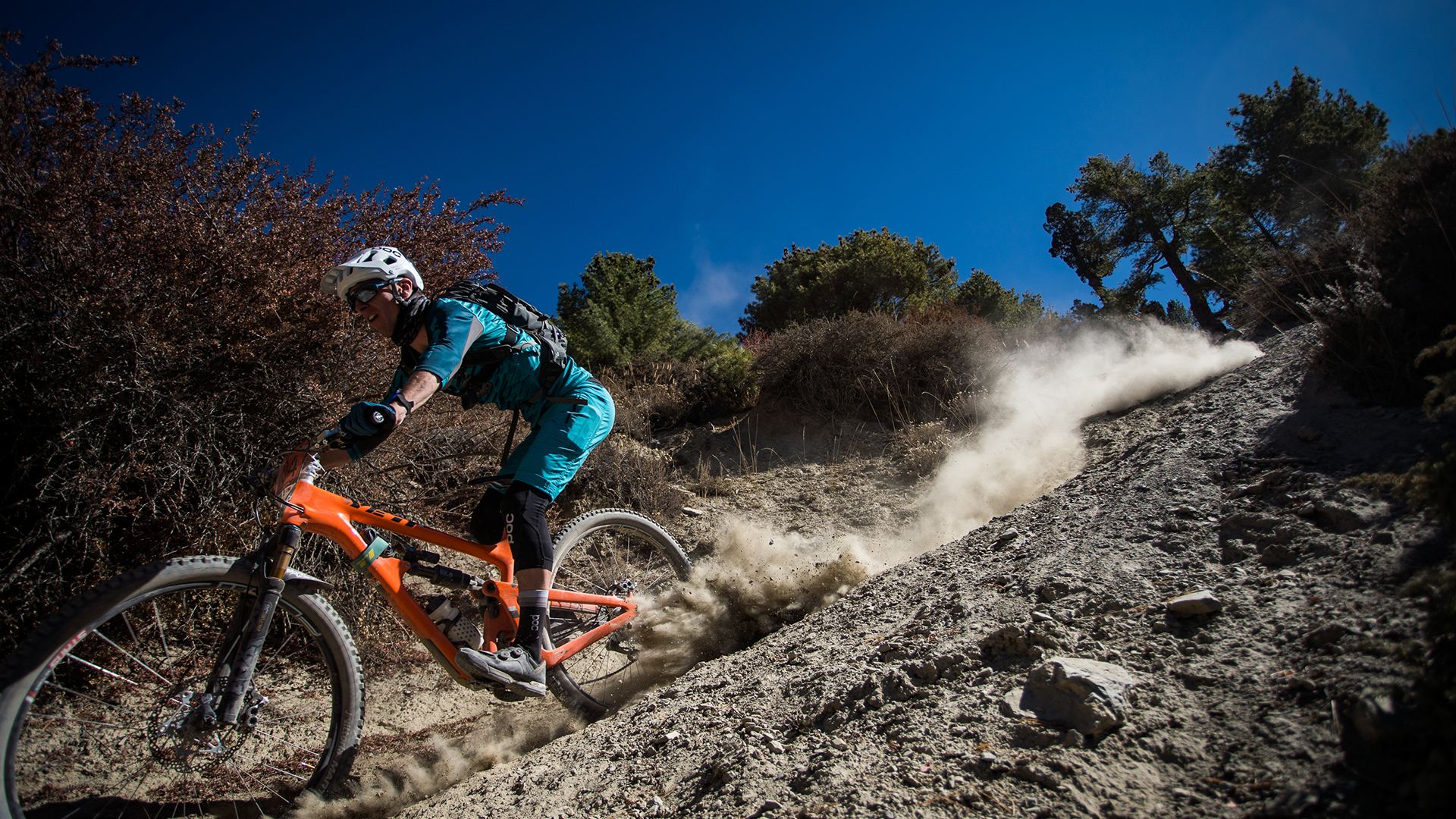 Tom Sampson sliding his orange bike through a dusty corner